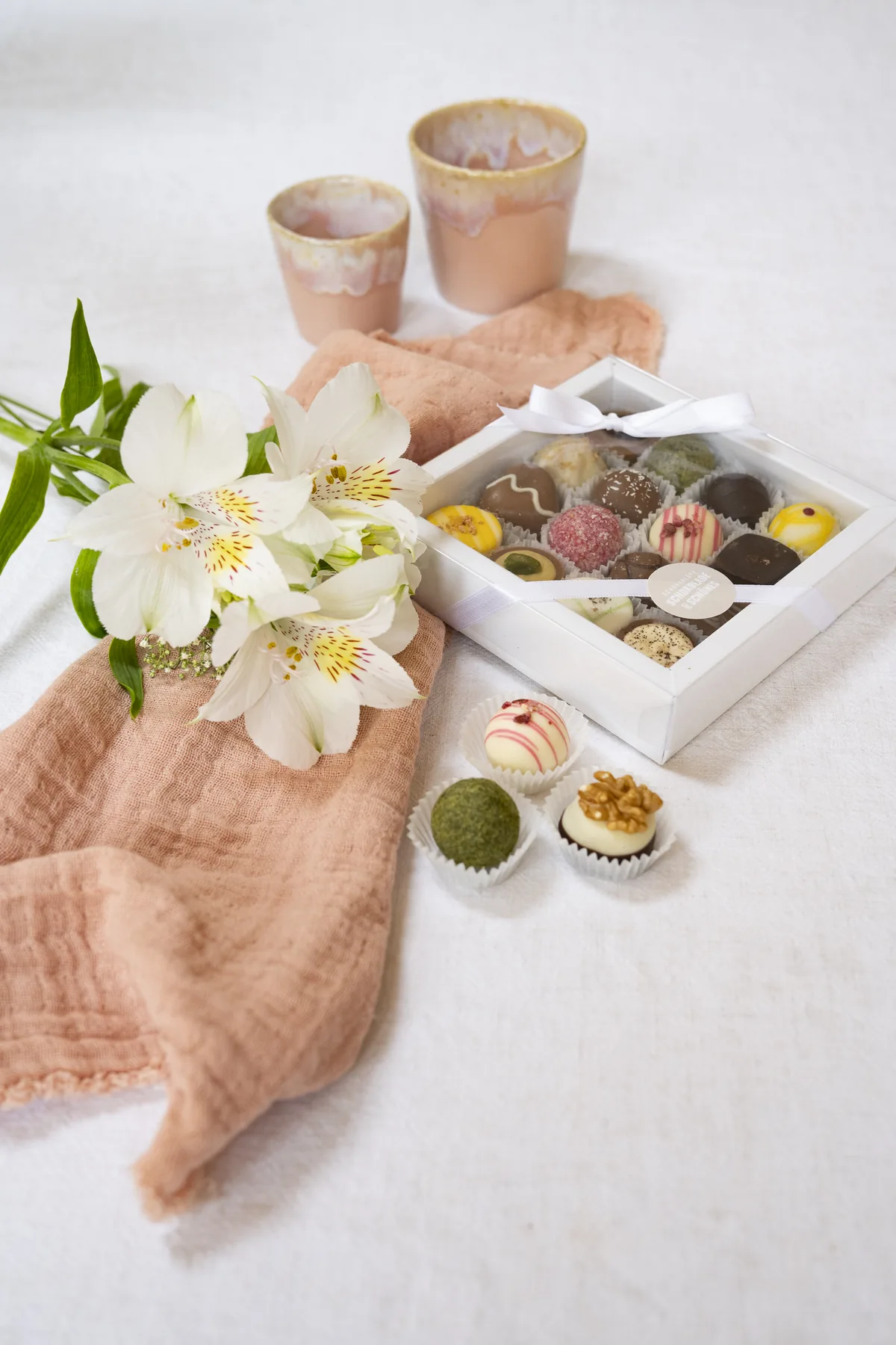 Geöffnete Pralinenschachtel der Schokoblüte mit Blüten und Leinentuch
